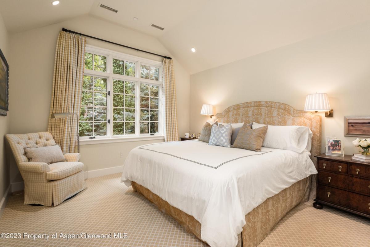 Bedroom with a large bed, chair and carpet flooring.