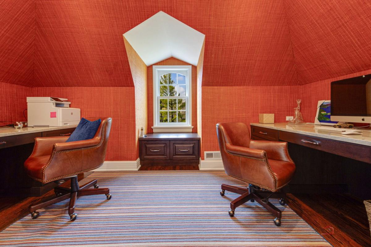 Home office with a red wall, computer and a large rug.