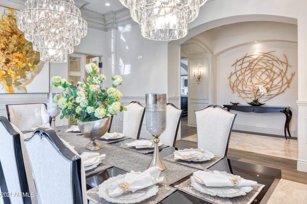 Dining room with a large table, chairs, chandelier and a large rug.