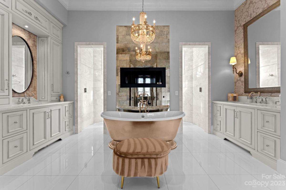 Bathroom with a dual sinks, mirrors, soaking tub and a chandelier.