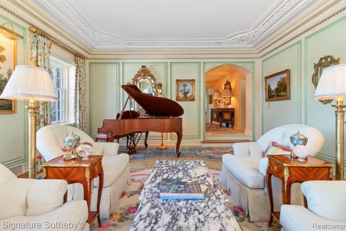 Living room with chairs, table and a piano.
