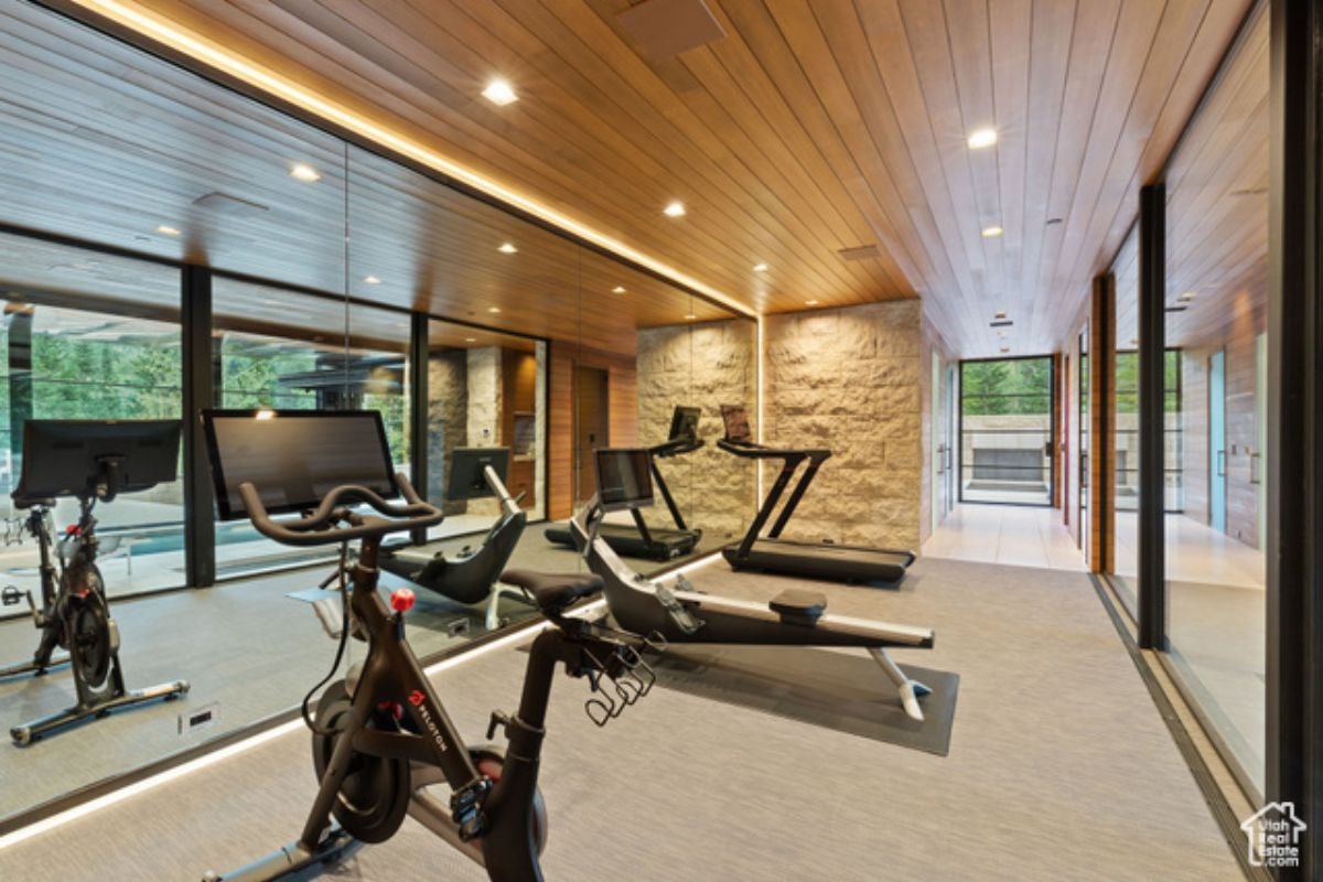 A home gym with a wooden ceiling, mirrors, and gym equipment.