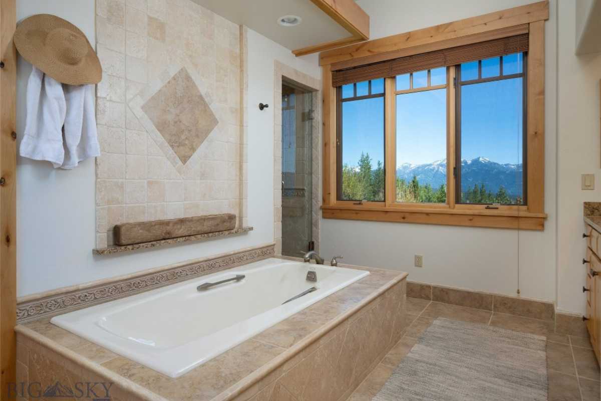 A bathroom with a bathtub, tiled floor, cabinet, and window.
