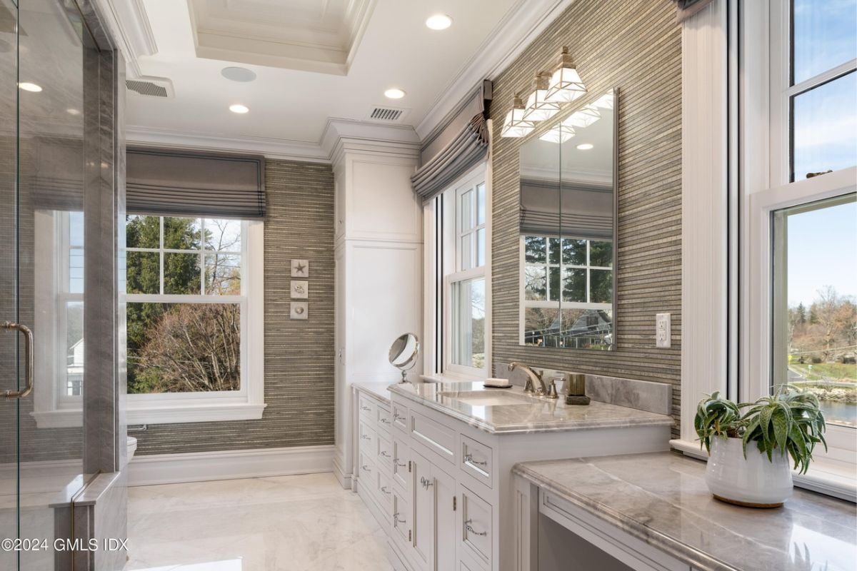 A kitchen with a window, sink, countertop, vase, shower room, mirror, and a white ceiling.