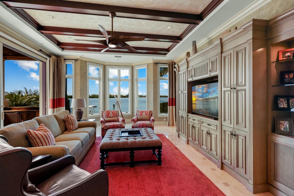 Living room with a couch, TV, glass windows and a large rug.