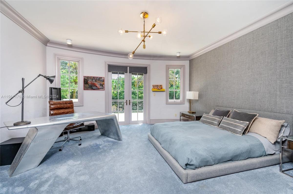 Bedroom with carpet flooring, chandelier and a desk.