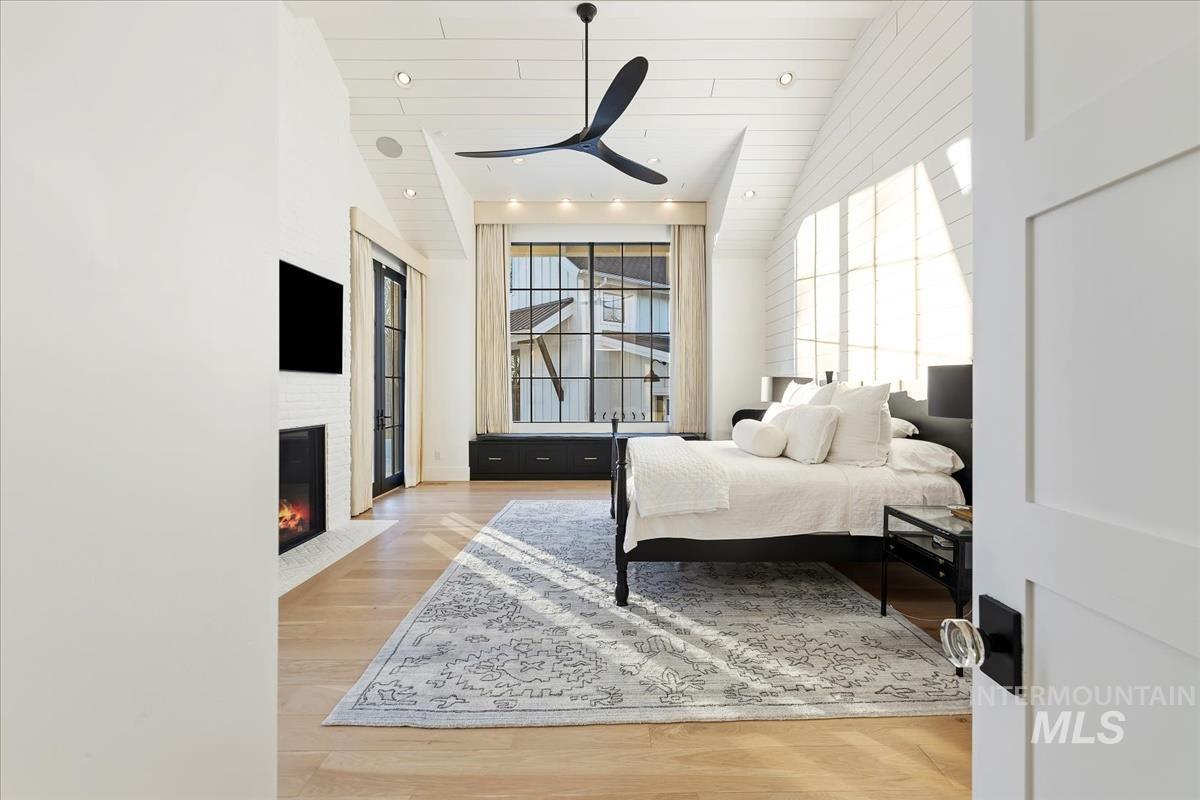 Bedroom with a large bed, large rug, ceiling fan and a glass window.