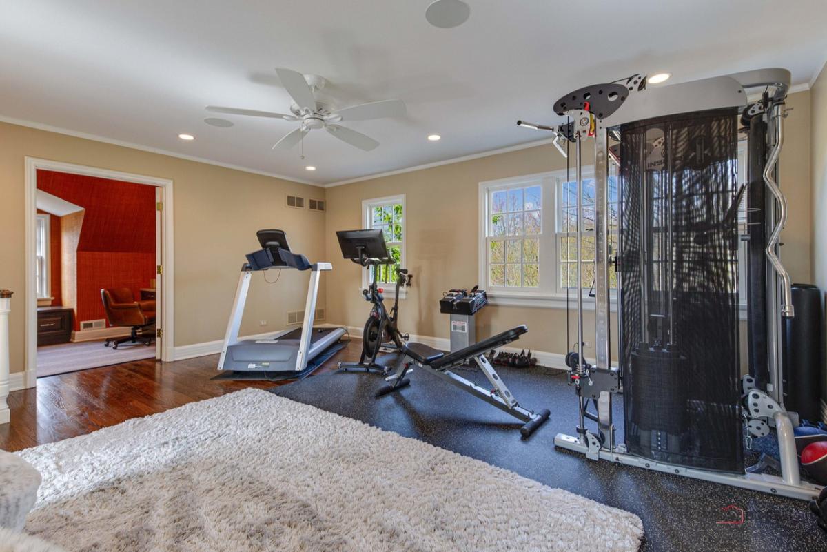 Home gym with workout equipment, custom lights, large rug and glass windows.