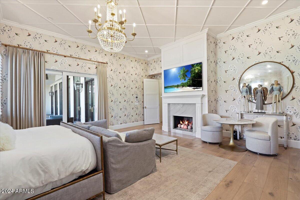 Bedroom with a large bed, chandelier, TV and a fireplace.