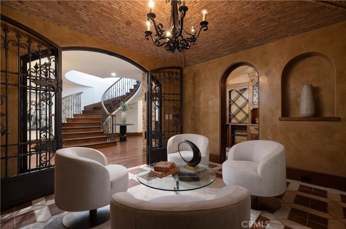 Lounge area with a glass table, chairs, chandelier and a staircase.