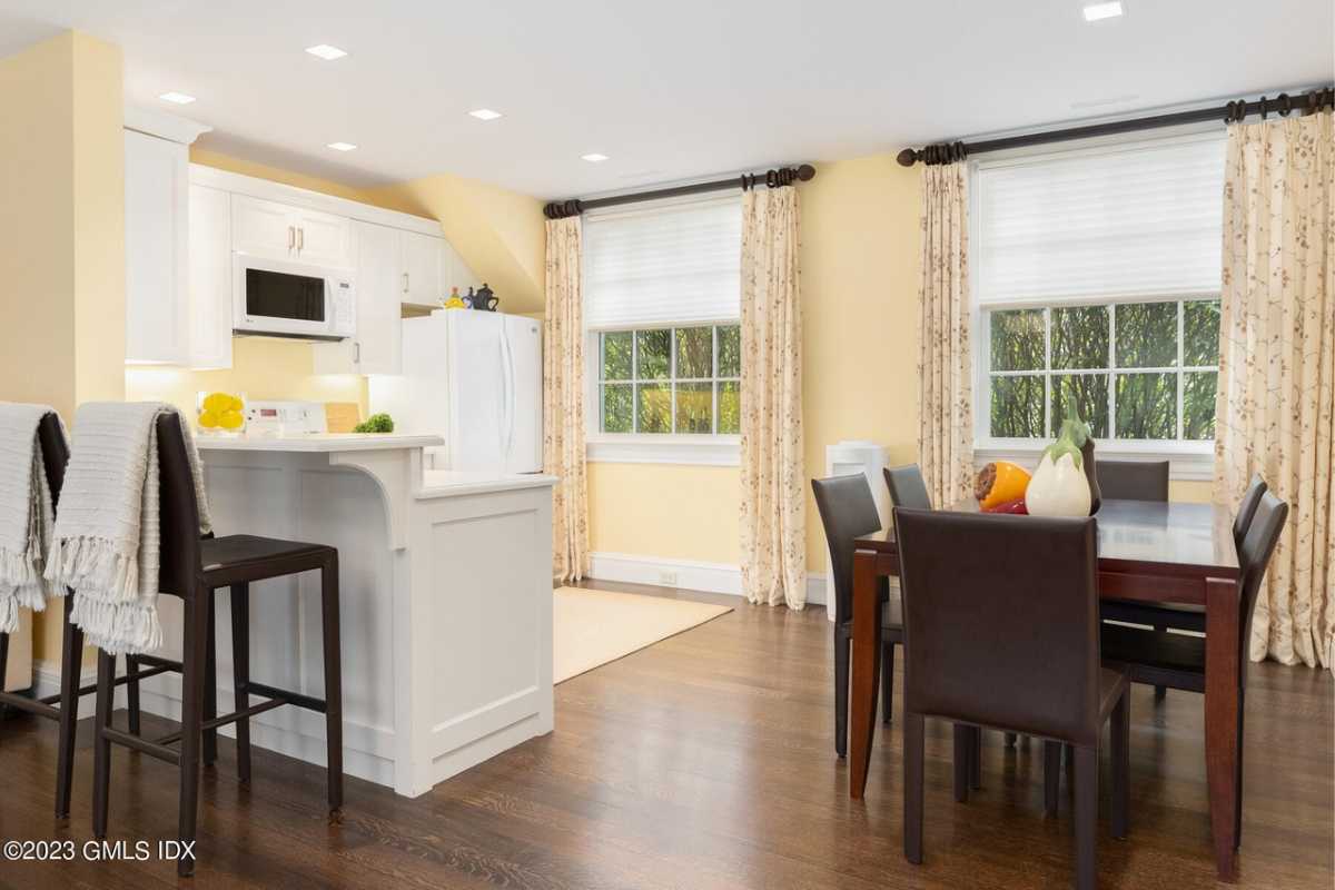 A kitchen and dining area with a wooden floor, windows, and a white ceiling.