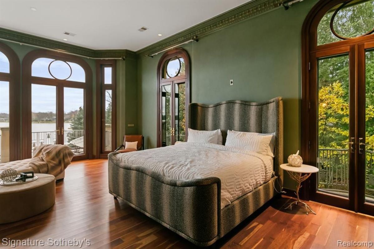 A bedroom with a bed, wooden floor, couch, and a white ceiling.