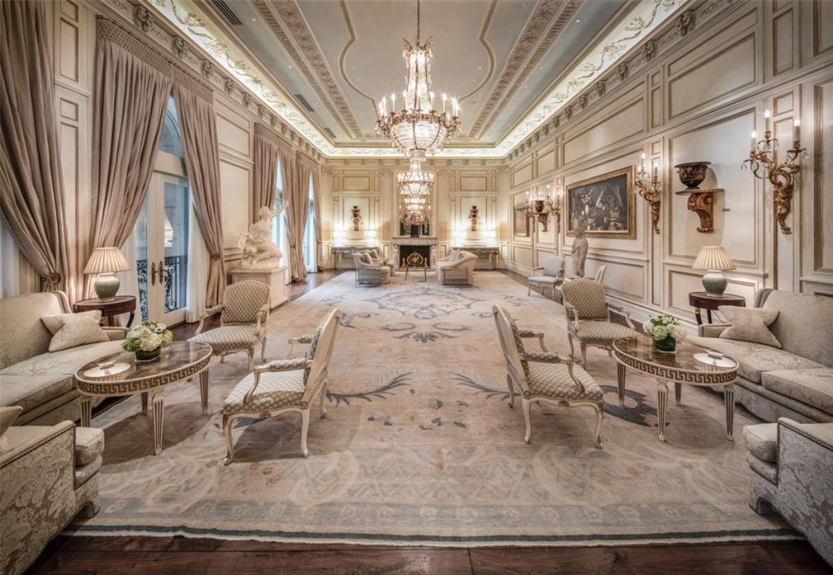 Great room with tables, chairs, chandelier and a large rug.