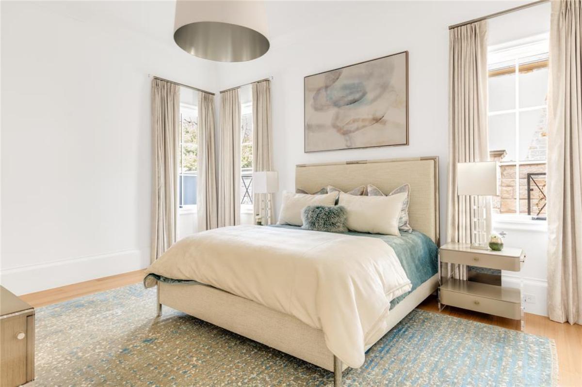Bedroom with wood flooring, a large rug and glass windows.