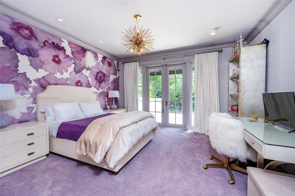 Bedroom with carpet flooring, chandelier and French glass doors.