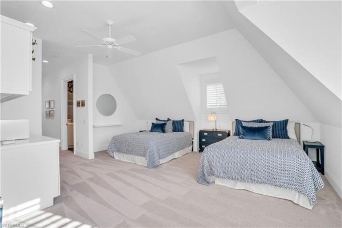 Bedroom with two beds, carpet flooring and ceiling fan.