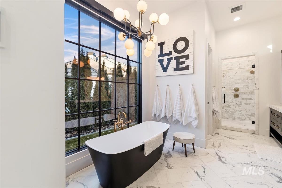 Bathroom with a soaking tub, chandelier and a large glass window.