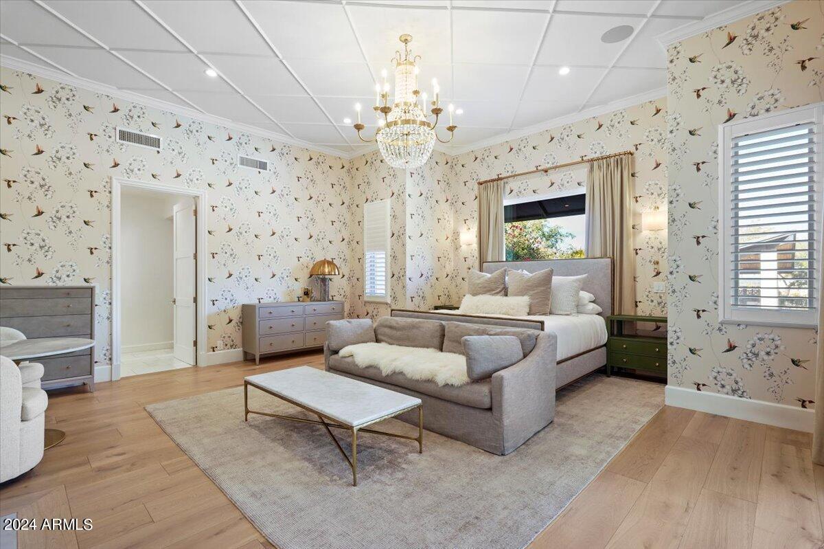 Bedroom with a large bed, chandelier and a couch.