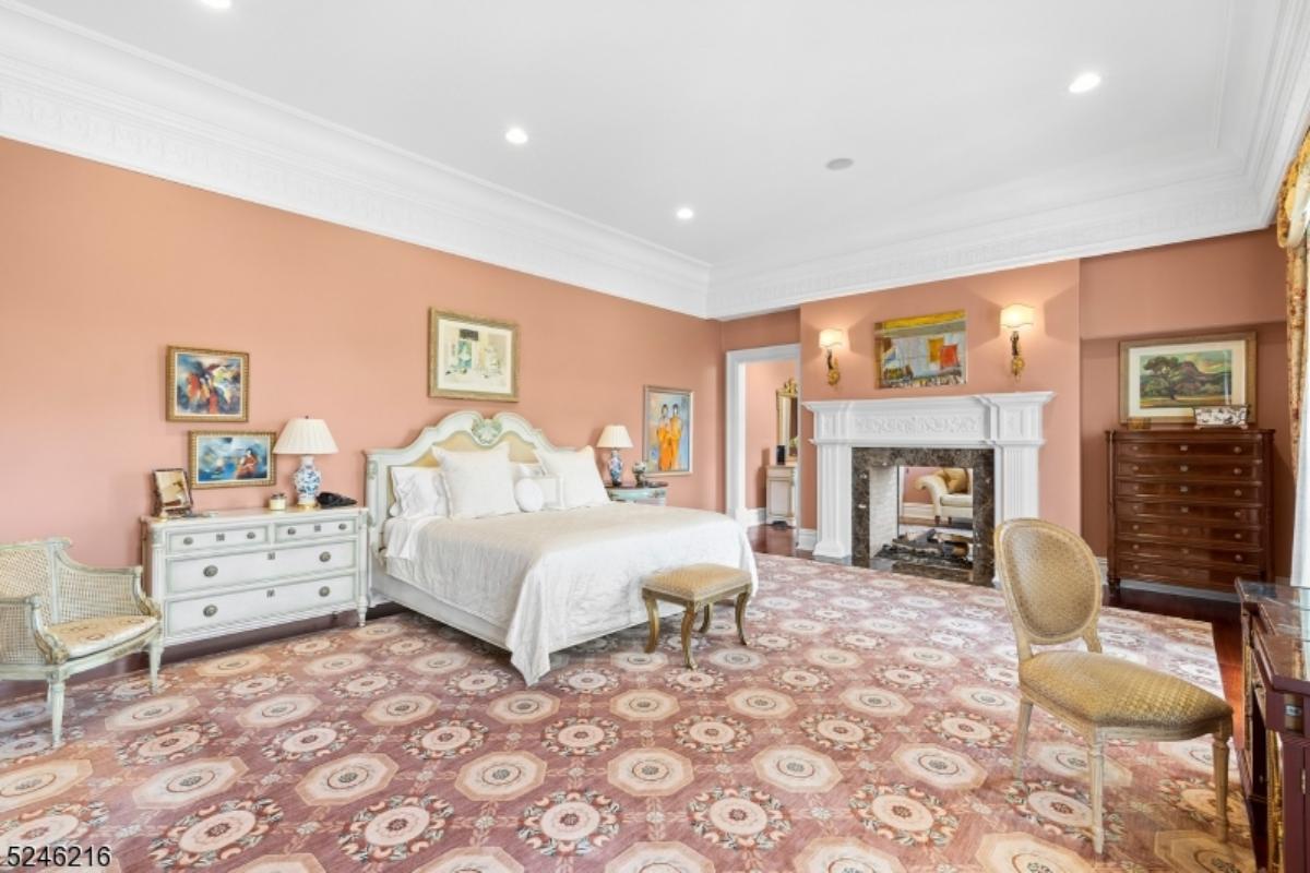 Bedroom with a large bed, custom lights, chairs and a fireplace.