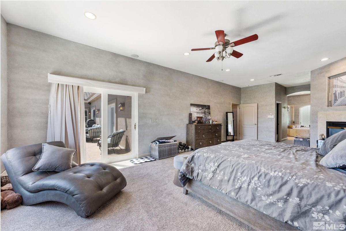 Bedroom with a large bed, ceiling fan, and carpet flooring.