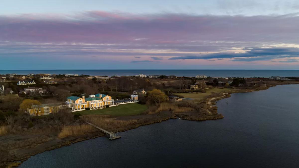 Aerial view of the mansion with a large lake and a boat dock.