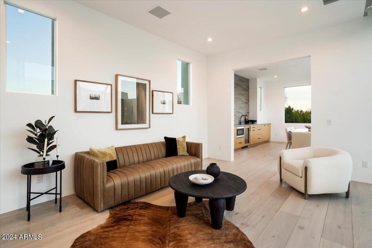 A seating area with a brown leather couch, chair, coffee table, wooden floor, and rug.