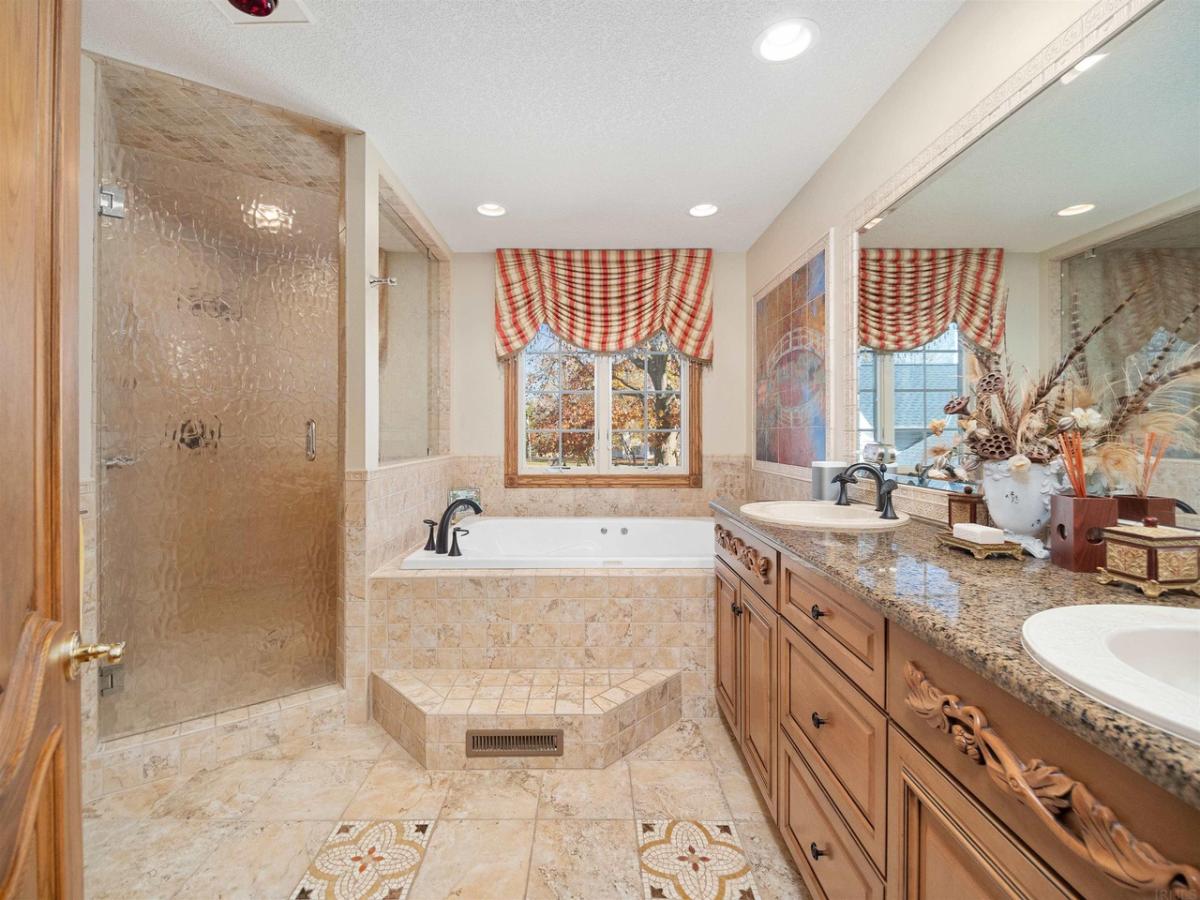 Bathroom with dual sinks, walk-in shower, soaking tub and custom lights.