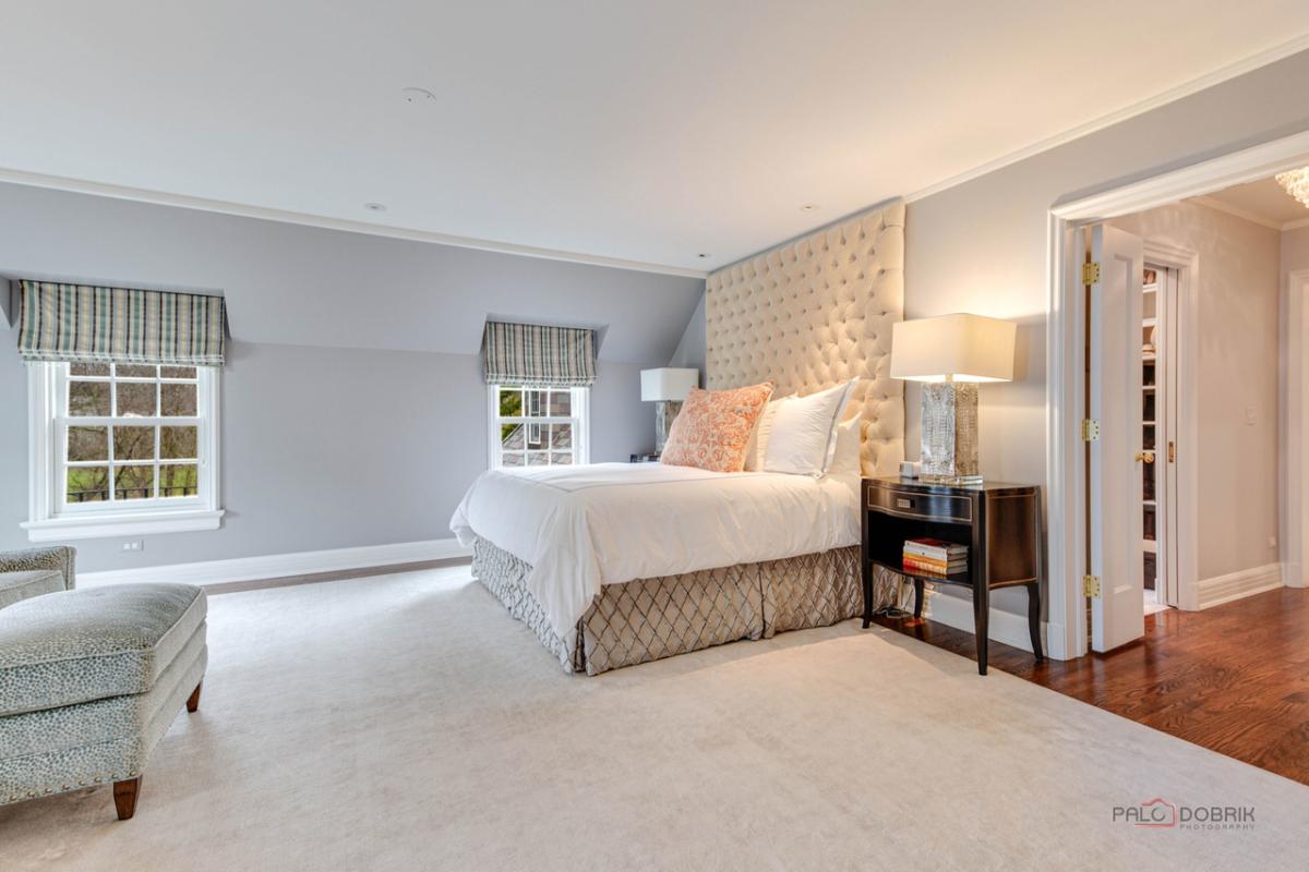 Bedroom with a large bed, glass windows, wooden door and a large rug.