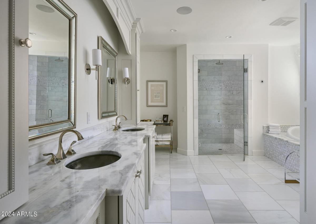 Bathroom with dual sinks, mirrors and tile flooring.