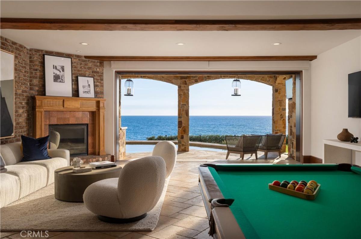 Entertainment room with a couch, chairs, fireplace and a pool table.