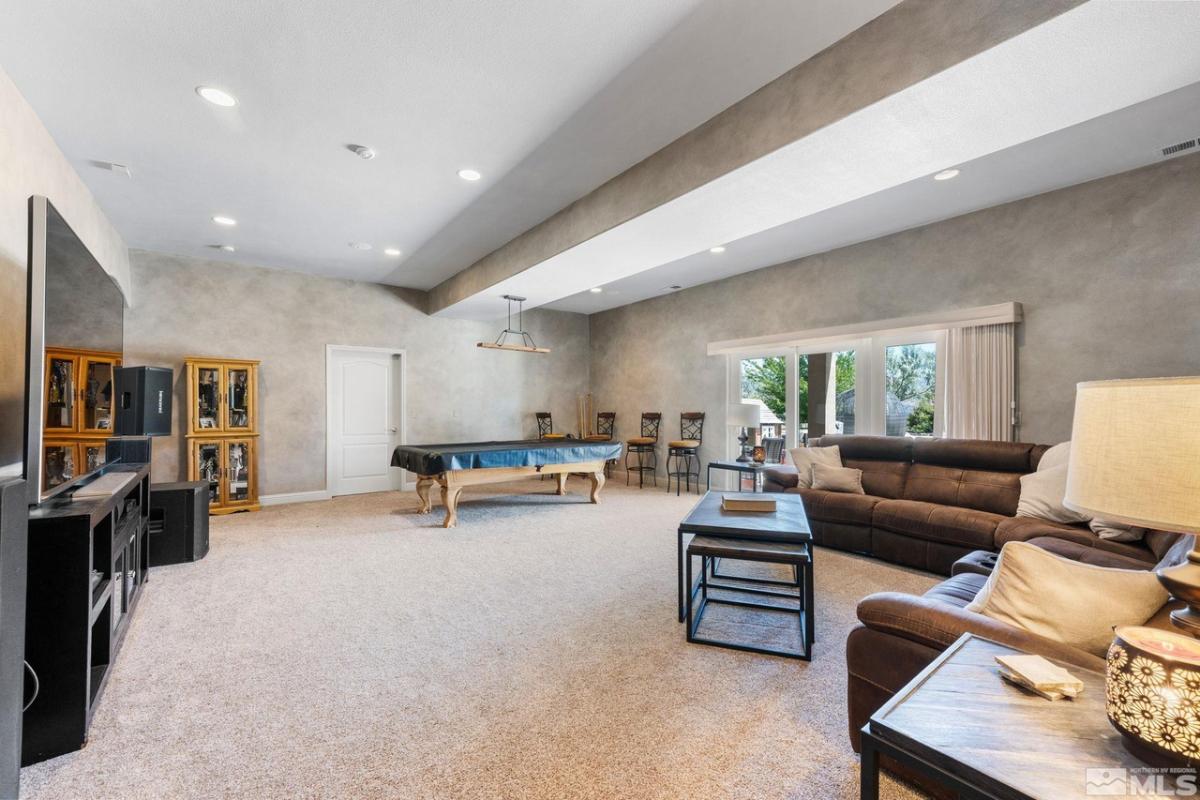 Entertainment room with couches, pool table, TV, and a carpet flooring.