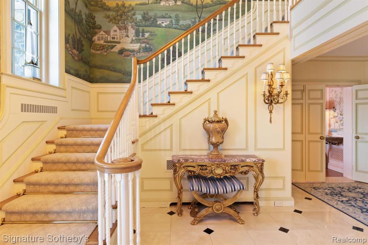 Foyer with a wooden door and a staircase.