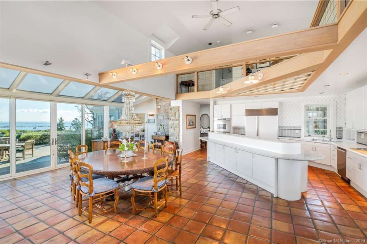 A kitchen with a tiled floor, a dining table, countertops, white cabinets, and kitchen appliances.