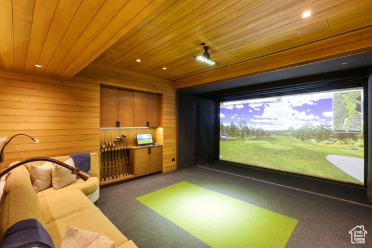 A home theater with wooden walls, wooden ceiling, couch, and large screen.
