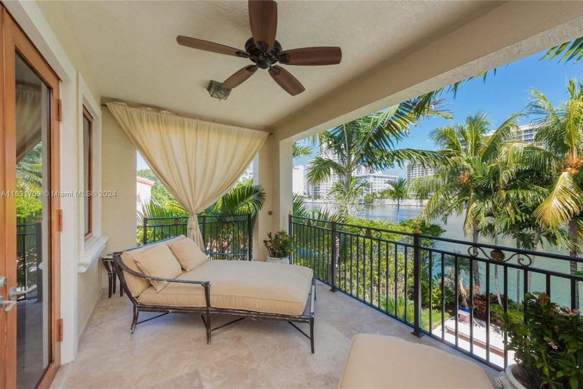 A balcony with a tiled floor, a ceiling fan, and a small bed.