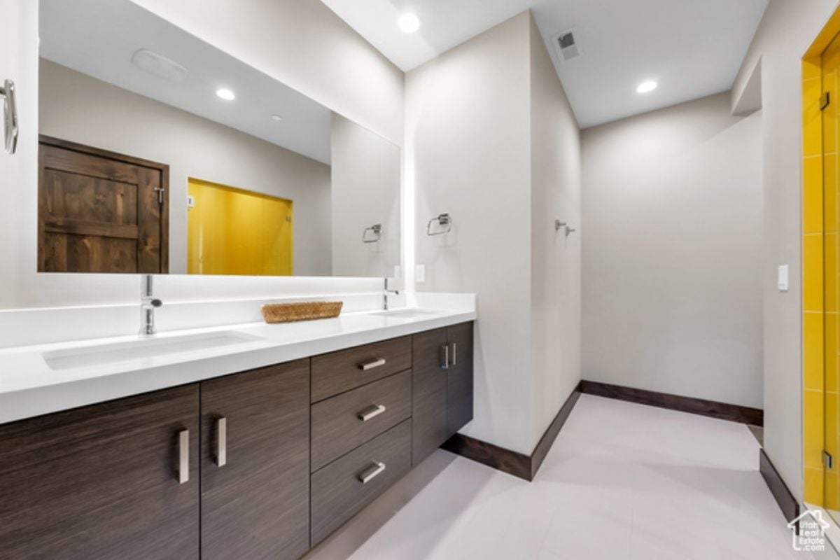 a white bathroom with large mirror, sink and cabinets