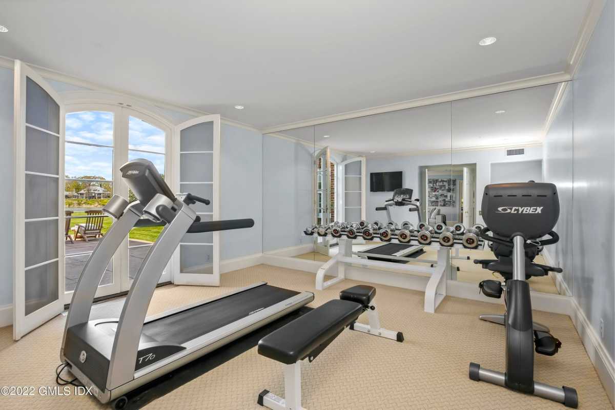A home gym with a large mirror, a white ceiling, and gym equipment.