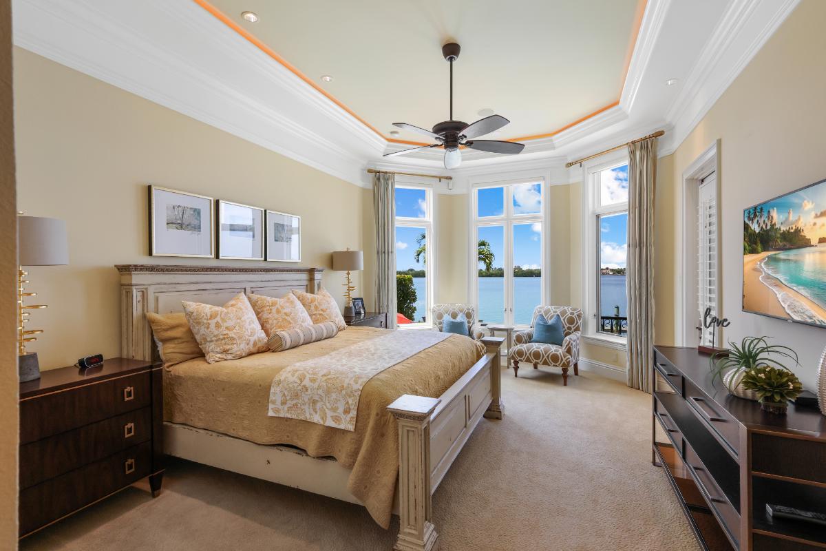 Bedroom with a large bed, carpet flooring and large glass windows.