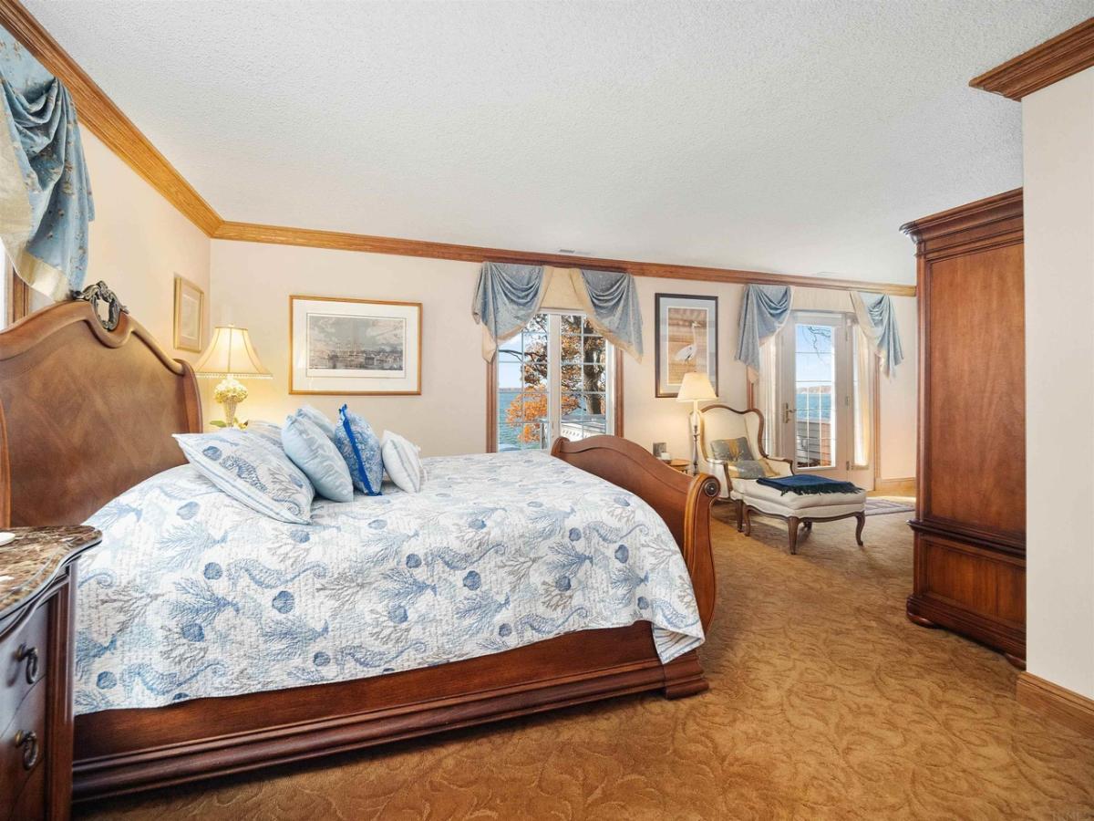 Bedroom with a large bed, glass windows and a carpet flooring.