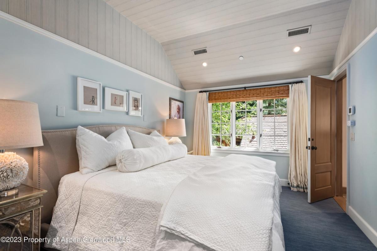 Bedroom with a large bed, custom lights and glass windows.
