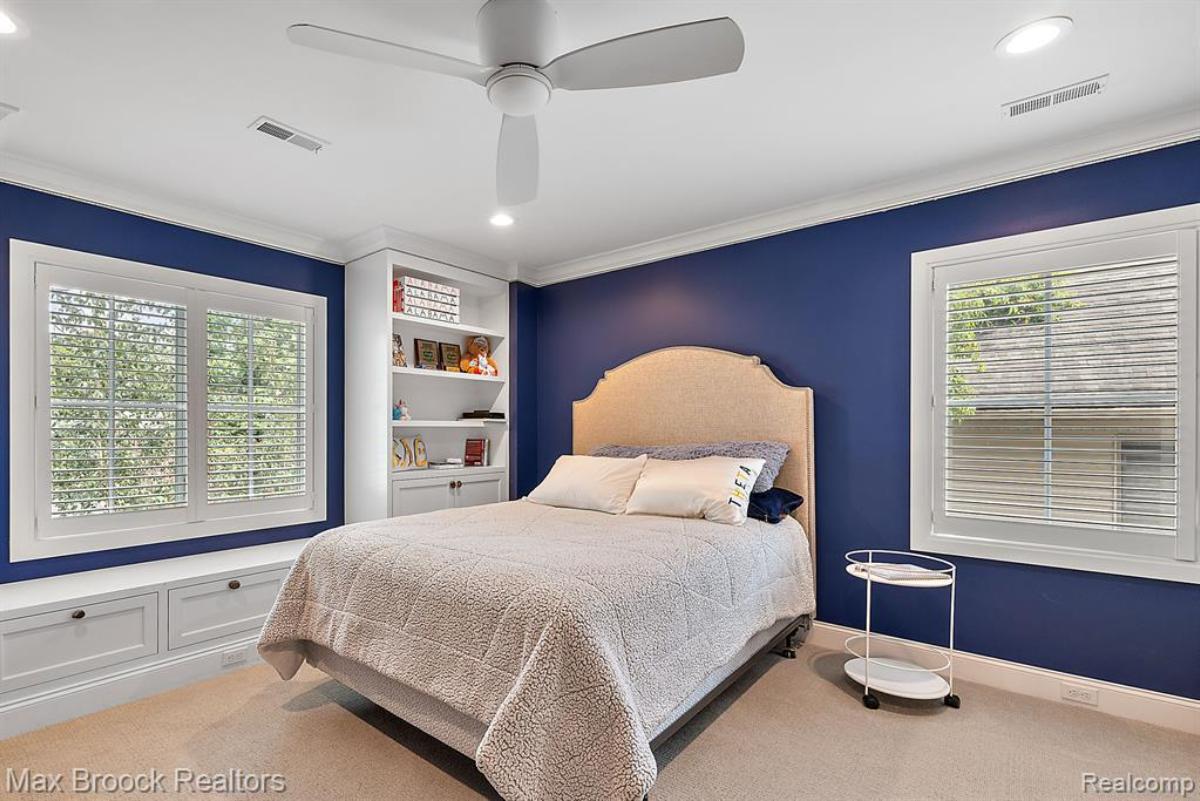 Bedroom with a large bed, custom lights, glass windows and carpet flooring.