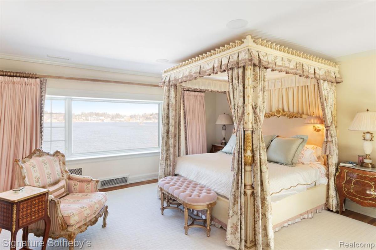 Bedroom with a large bed, chair, large rug and a glass window.