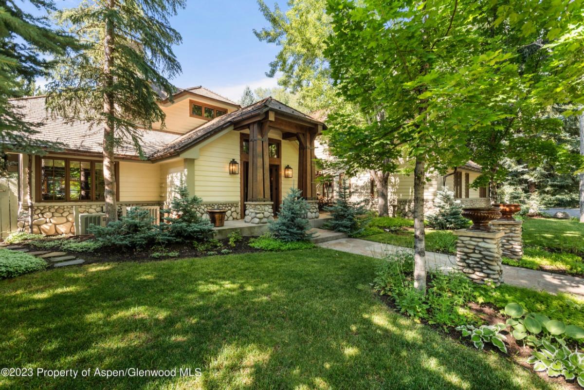 Front yard with a large green lawn and trees.
