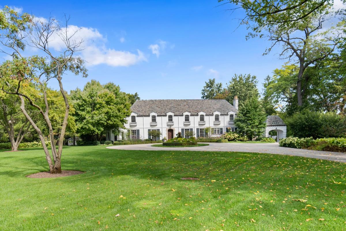 Front view of the mansion with a large lawn and a spacious driveway.