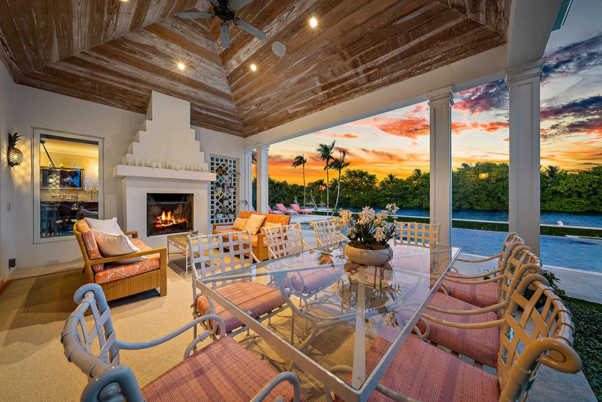 Covered patio with a fireplace, glass table and chairs.