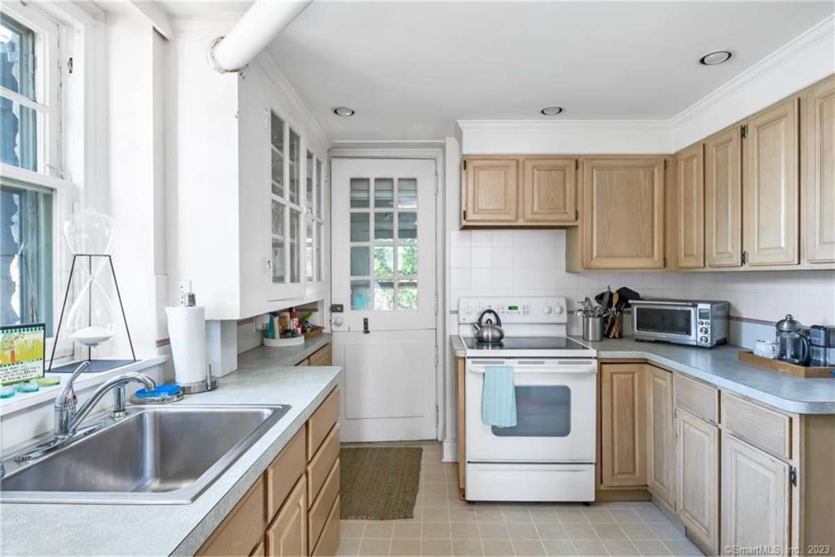 A small kitchen with a sink, countertop, cabinets, and kitchen appliances.