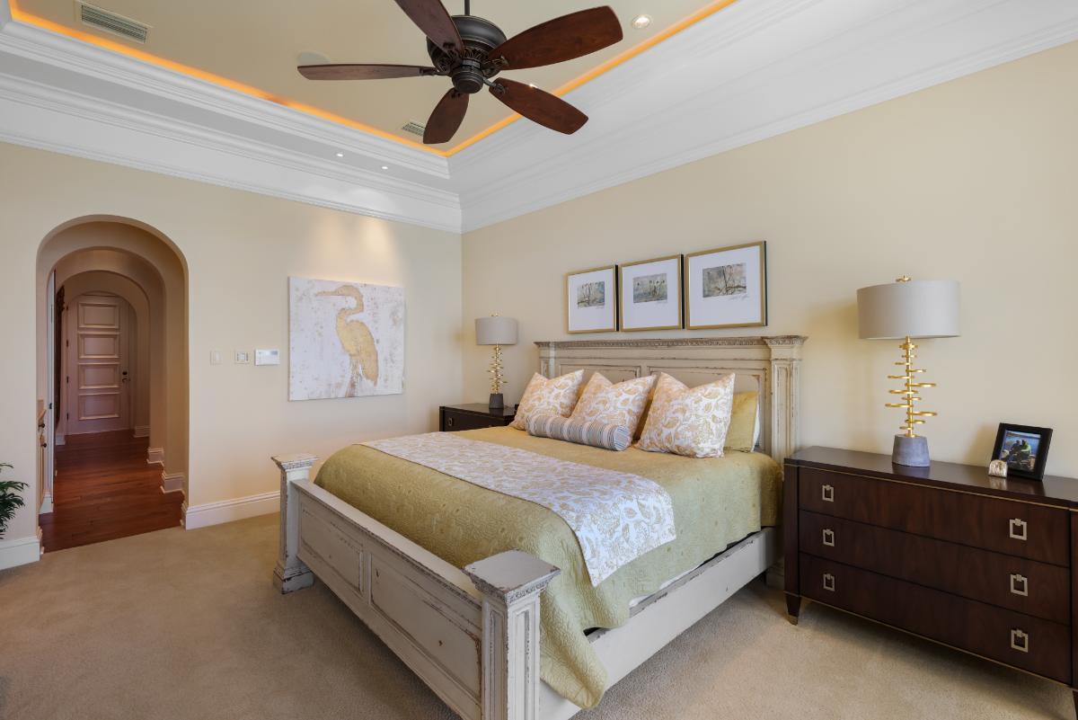 Bedroom with a large bed, carpet flooring and a ceiling fan.