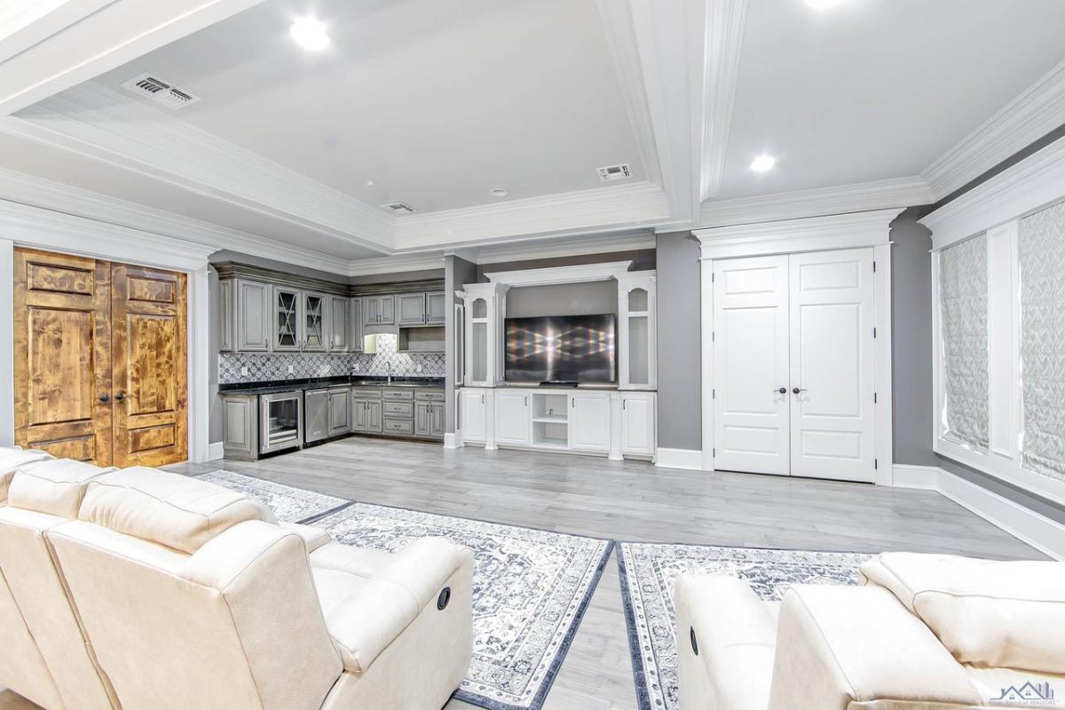 Living room with couches, custom lights, TV and wooden doors.