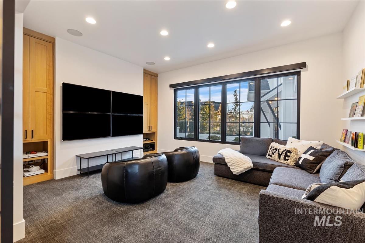 Living room with couches, TV, glass windows, custom lights and a carpet flooring.