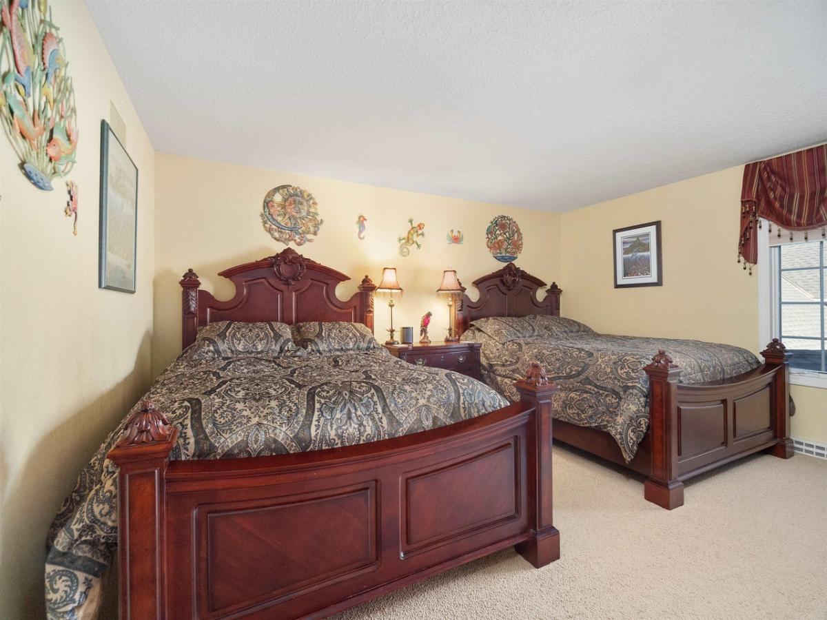 Bedroom with two beds, glass window and carpet flooring.